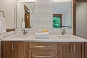 Modern bathroom with wooden cabinetry and dual sinks.