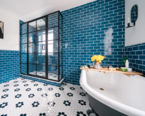 Bright bathroom with blue tiled walls and vintage floral floor tiles.